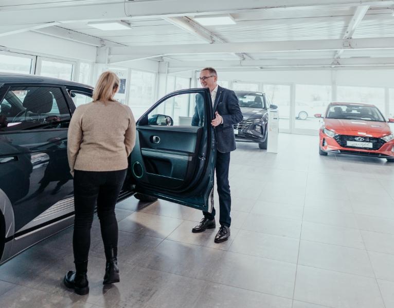 Autoverkäufer zeigt einer Kundin ein Hyundai-Fahrzeug im Showroom des Autohaus Engel