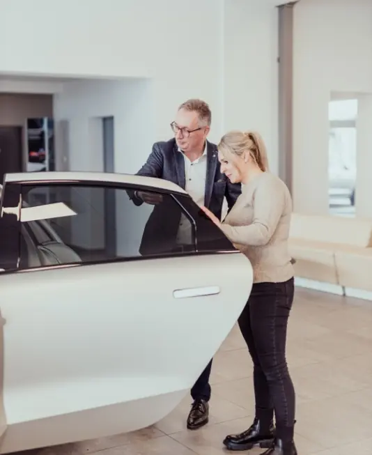 Autoverkäufer zeigt Kundin den Innenraum eines Hyundai-Elektroautos im Autohaus